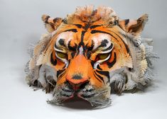 an orange and black tiger mask on a white surface with one eye open, the other half closed