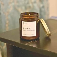 a candle sitting on top of a wooden table next to a jar with a label