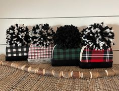 four plaid bags with pom - poms are lined up on a wicker mat