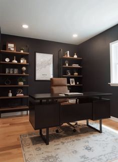 a home office with black walls and shelving units on either side of the desk