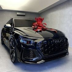 a black audi car with a red bow on it's hood in a garage