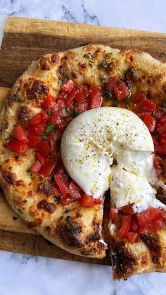 a pizza with cheese and tomatoes on a cutting board