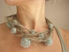 a close up of a woman wearing a necklace that has balls on it and rope around the neck