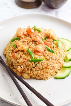 a white plate topped with rice and veggies next to chopsticks