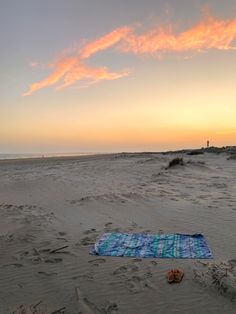 a towel and flip flops on the beach at sunset