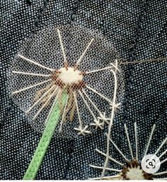 a dandelion with two needles sticking out of it's center, on a piece of blue fabric