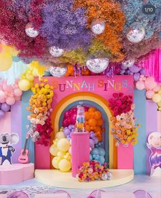 there is a colorful stage set up with balloons and streamers on the ceiling for children's birthday party