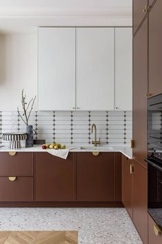 a kitchen with brown cabinets and white tile backsplash, gold trimmings