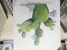 a painting of a green frog with flowers on it's back and arms, sitting on top of a table