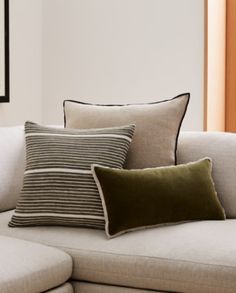 three pillows sitting on top of a white couch