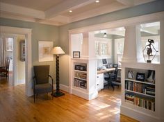 a living room filled with furniture and bookshelves next to a doorway that leads to another room