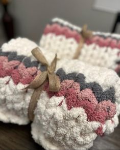 two crocheted dishcloths are sitting on a wooden table with a brown ribbon