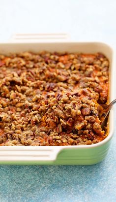 a green casserole dish filled with oatmeal and meat toppings