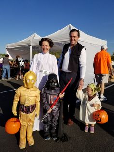 a man and woman standing next to a child dressed up as star wars characters with pumpkins