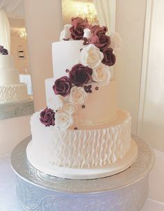 a three tiered wedding cake with purple and white flowers on the top, sitting on a silver platter