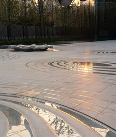 the sun shines brightly on an artisticly designed circular area in front of a building