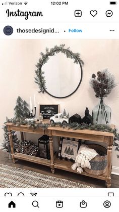 a wooden table with christmas decorations on top and a round mirror above it that says farmhouse