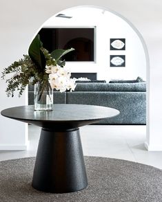 a vase with flowers sitting on top of a table in front of a couch and coffee table