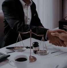 two people shaking hands in front of an hour scale and a calculator on a table