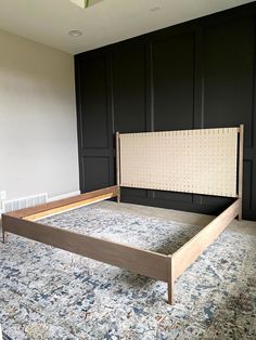 a large bed sitting in the middle of a room next to black cupboards and an area rug