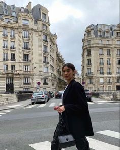 a woman crossing the street in front of some buildings