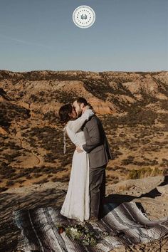 a bride and groom kissing in the desert