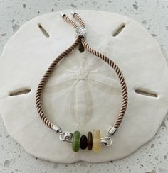 This is an adjustable slider bracelet that features silver plated slider  beads on a black cord.  The handmade sterling silver bar holds 4 assorted color pieces of seaglass. Sea Glass Bracelet, Slider Bracelet, Silver Bar, Silver Bars, Handmade Sterling Silver, Sea Glass, Sliders, Silver Plate, Silver Plated