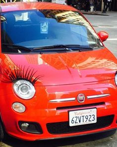 an orange car with fake eyelashes on the front