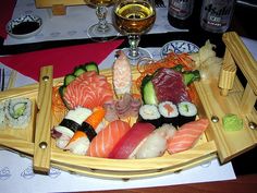 sushi platter with chopsticks and wine glasses on the table next to it