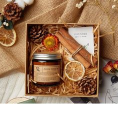 an orange and cinnamon gift set in a wooden box with pine cones, cinnamon sticks, lemon slices, and cloves