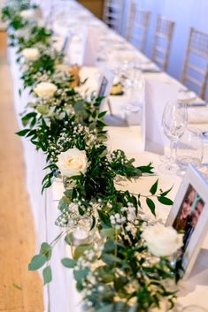 the long table is decorated with white flowers and greenery