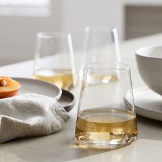 two glasses of wine on a table next to plates and bowls with food in them