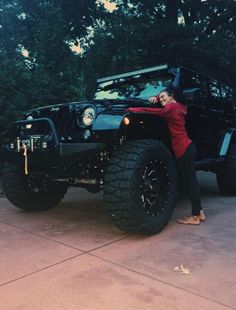 a woman standing next to a black jeep