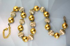 Vintage Gold Beads For Festive Occasions, Festive Vintage Gold Beads, Vintage Gold Beaded Necklace With Lobster Clasp, Vintage Gold Beads For Party, Retro Gold Necklaces With Round Beads, Retro Gold Necklace With Round Beads, Retro Gold Beaded Necklace For Gift, Retro Gold Beaded Necklaces For Gifts, Abstract Pendant