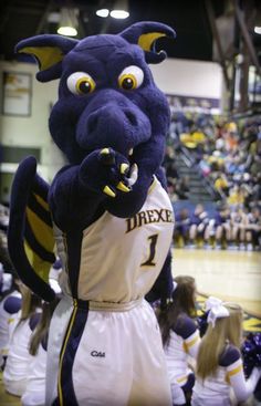 a mascot is standing on the court with his hands in his mouth and looking at the crowd