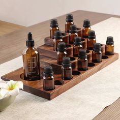 a wooden tray with bottles on it and a white flower in the middle next to it