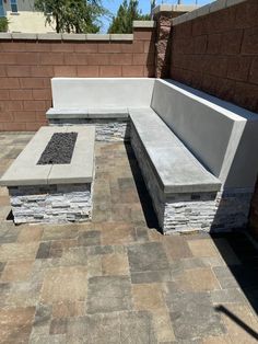 a stone bench sitting next to a fire pit on top of a brick floored patio