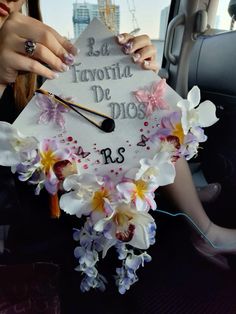 a woman sitting in the back seat of a car holding a graduation cap with flowers on it