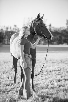 a woman standing next to a horse in a field