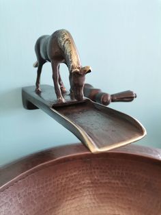 a horse figurine is on top of a metal object in front of a blue wall