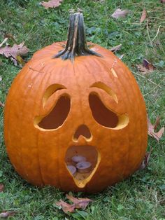 a carved pumpkin with its mouth open in the grass