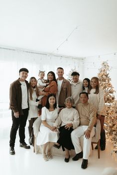 a group of people standing next to each other in front of a christmas tree