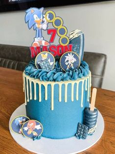 a birthday cake with blue icing and sonic the hedgehog decorations on top is sitting on a table