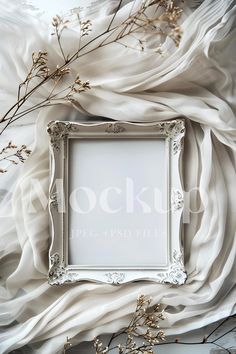 a white frame sitting on top of a bed next to dried flowers