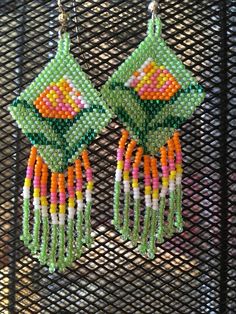 the earrings are made out of beads and beaded with green, pink, yellow and orange flowers