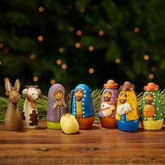 a group of small figurines sitting on top of a wooden table next to a christmas tree