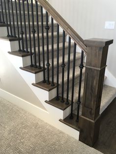 the stairs are made of wood and have metal balustiers on them, along with carpeted flooring