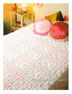 a white crocheted bedspread with pink pillows