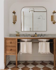 a bathroom with two sinks and a mirror on the wall next to it is decorated in white and gold