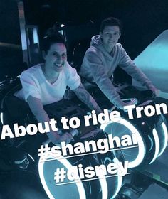 two people sitting on top of a car in front of a neon sign with the words about to ride from shanghai disney